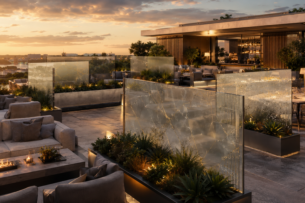 Modern rooftop terrace with glass walls, outdoor furniture, and cityscape view during sunset.
