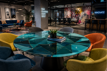 Modern interior with a round blue glass table and colorful chairs in a stylish setting.